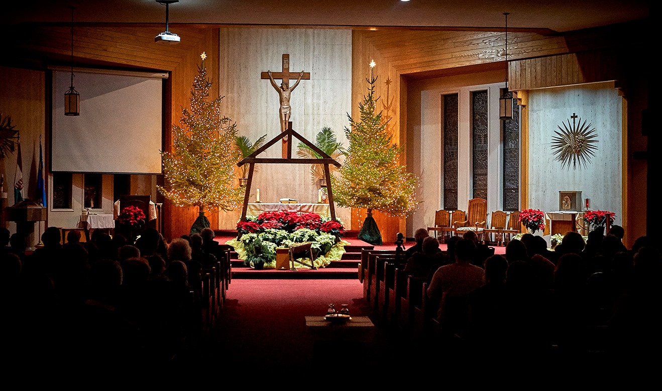 Two Christmas trees and the frame of a barn decorate the altar